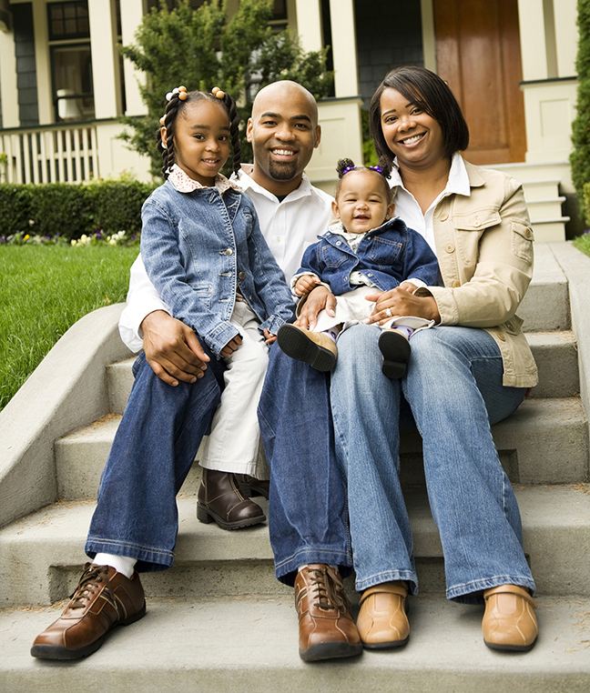 African American family smiling, sitting on front steps of house