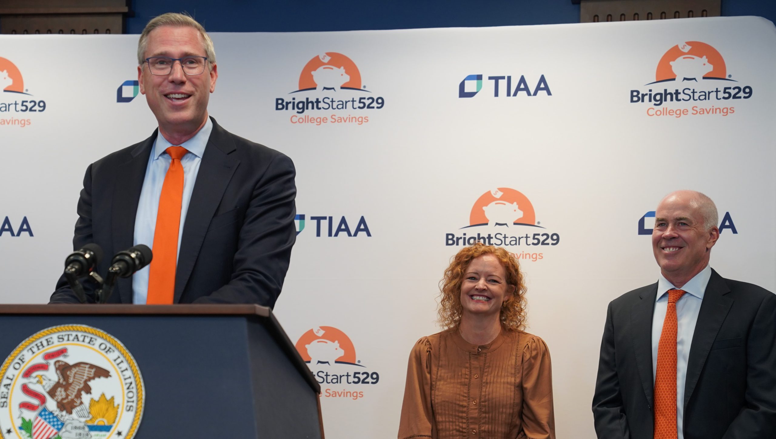 Treasurer Frerichs speaking at a podium with a Bright Start backdrop and a woman and man behind him