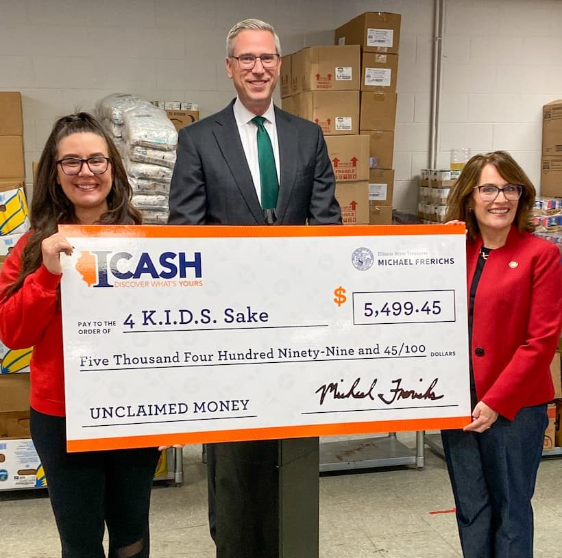 Frerichs returns unclaimed money to 4 Kids Sake charity with two women in red holding a giant check