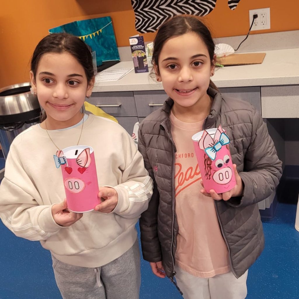 Two sisters hold up their banks from the Rockford 5.29 Museum Days