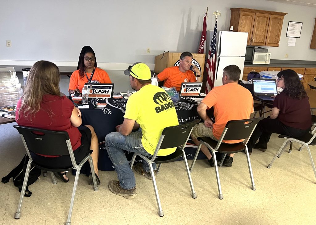 a team of people sitting at a long table meeting with the public