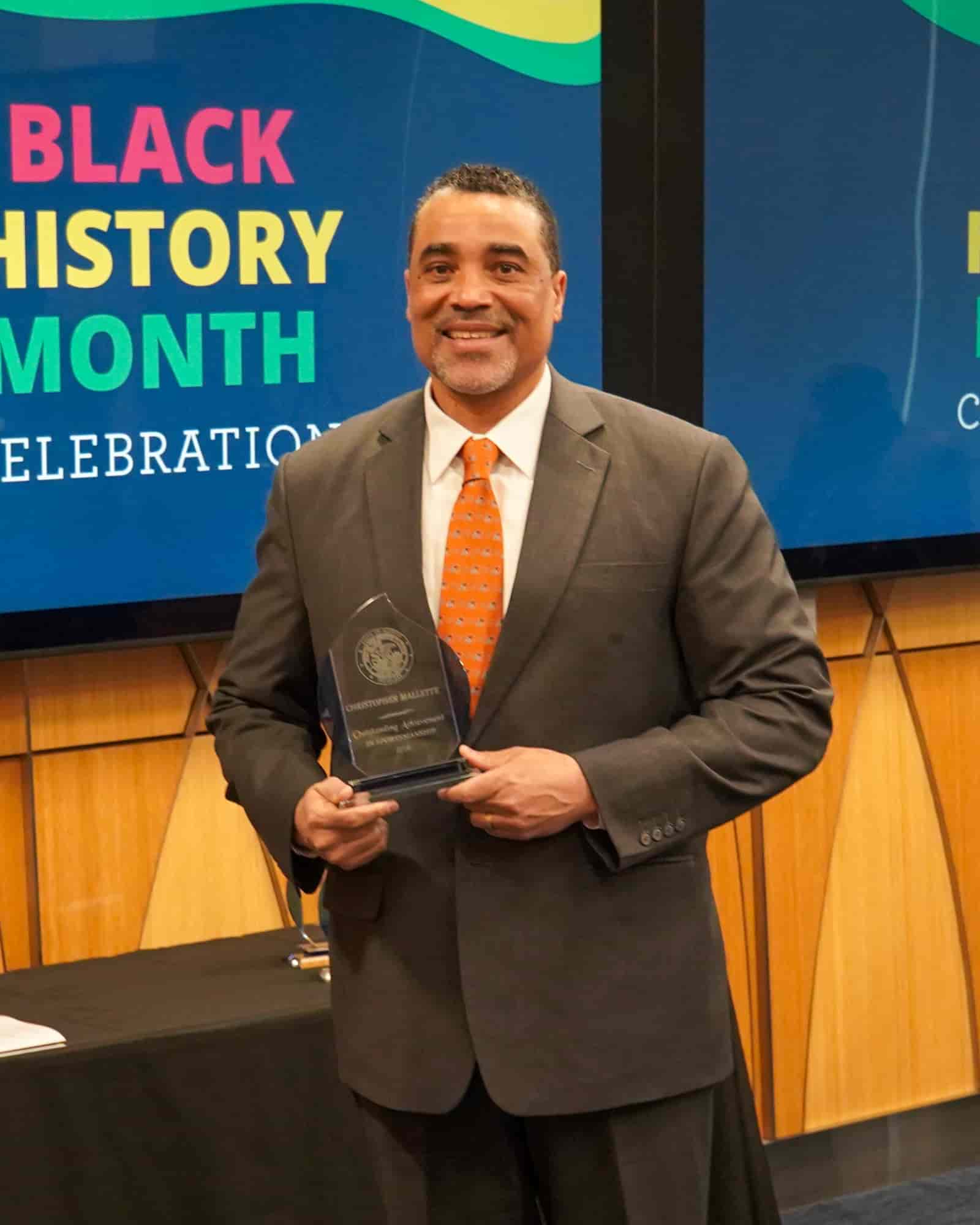man in suit smiling and holding an award