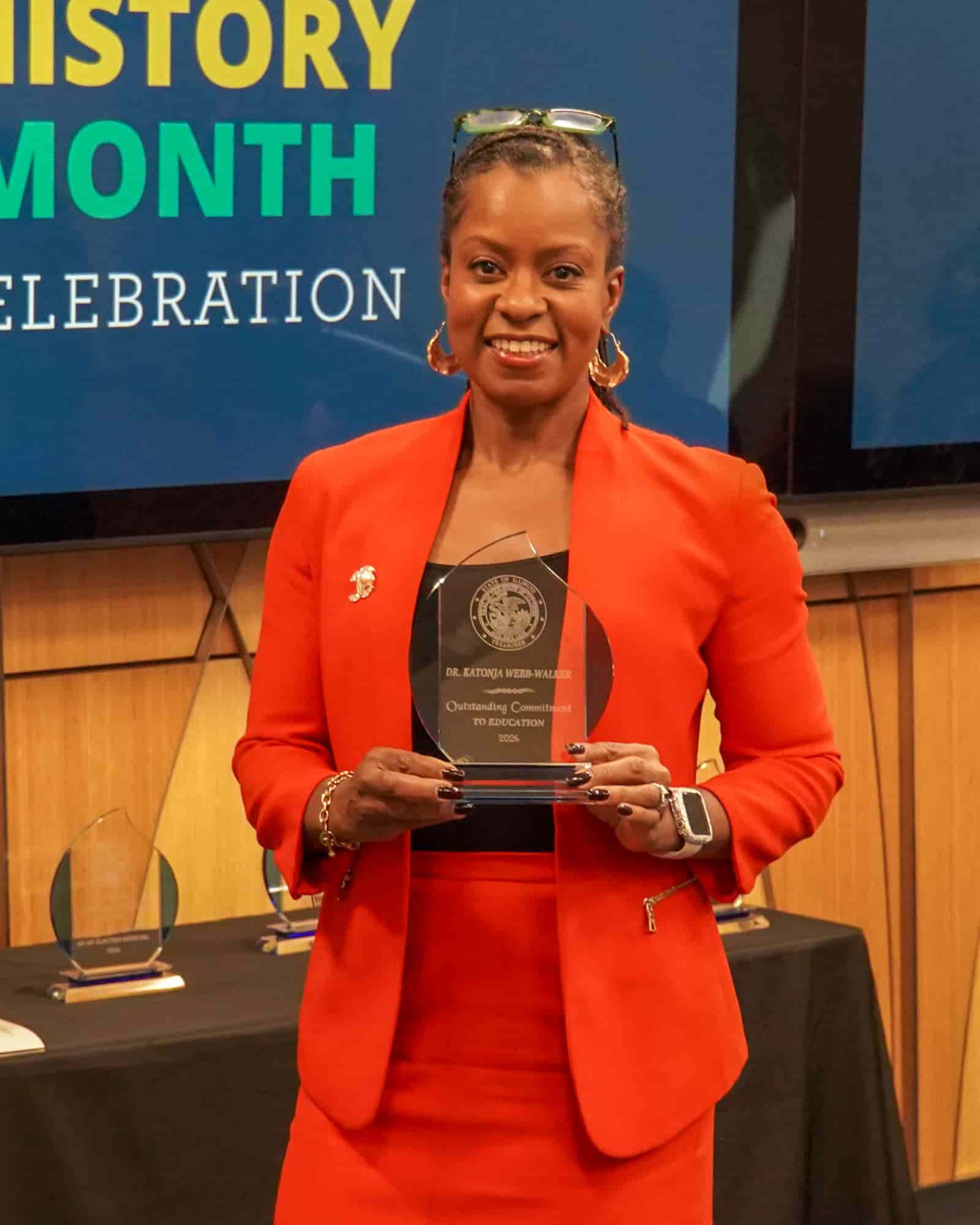 woman in suit holding award and smiling with pride