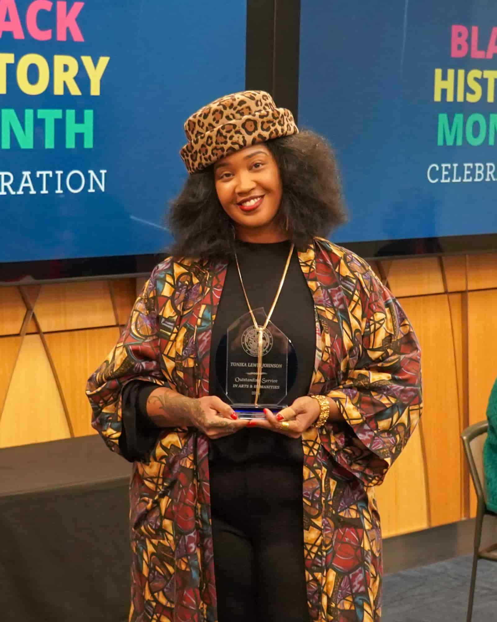 award winner wearing stylish hat smiling at the camera holder her award