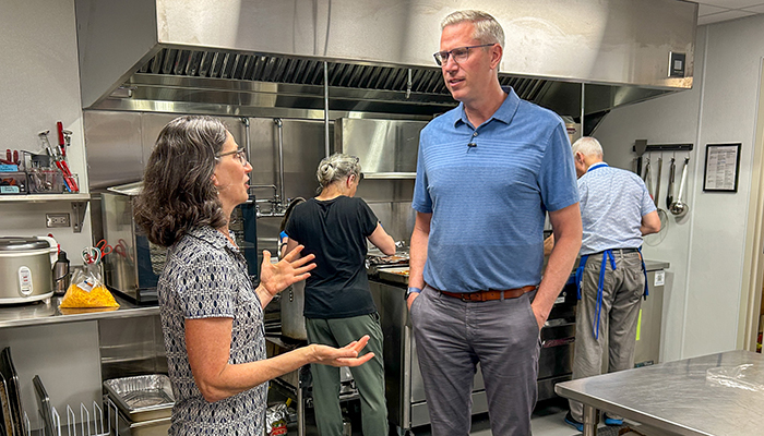 Treasurer Frerichs speaks with a woman in the kitchen of a food pantry and service agency
