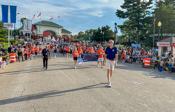 Treasurer Frerichs marches down a street at the Illinois State Fairgrounds during the twilight parade as crowds line the street.