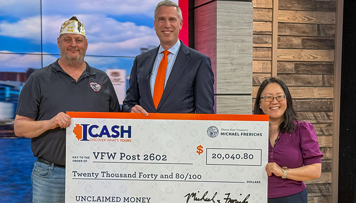Treasurer Frerichs stands with a man and a woman, all holding a giant check for ,040