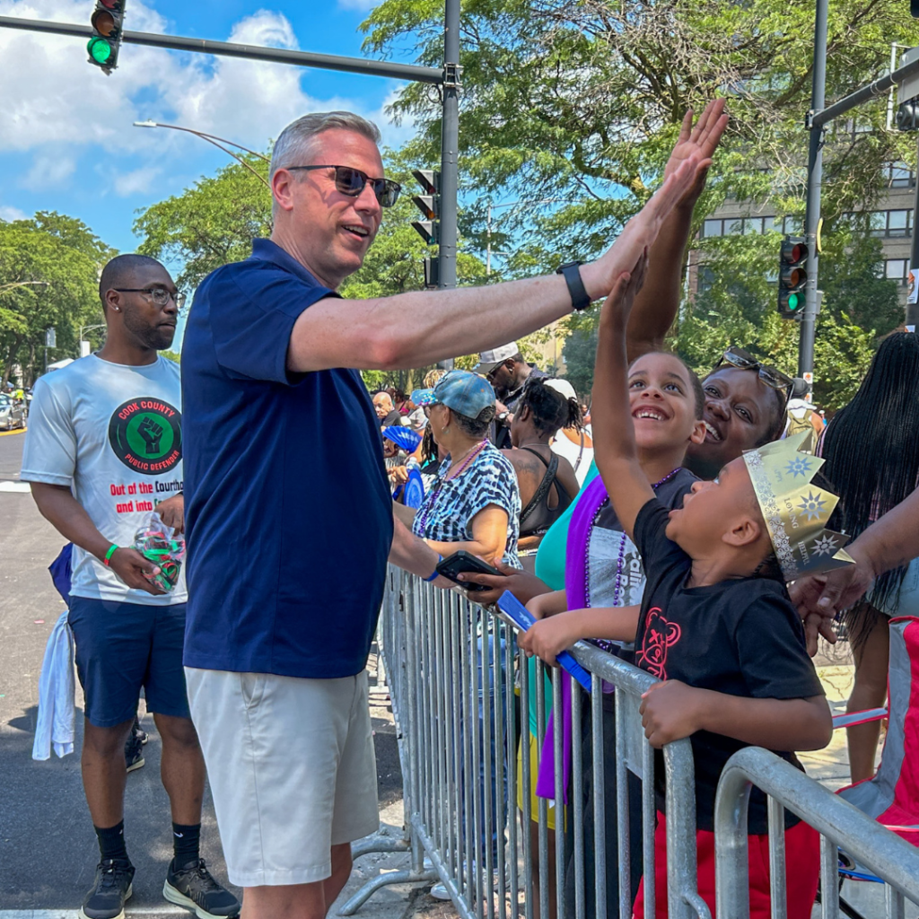 Treasurer Frerichs giving a child a high five at the Bud Billiken Parade. 
