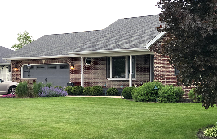 A brick house with a black roof and a tidy green lawn